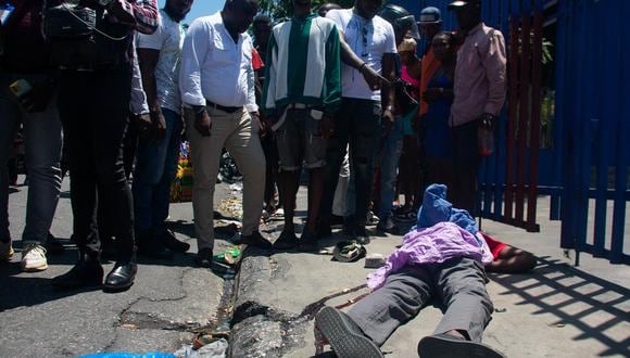 La gente mira el cuerpo de una persona que recibió un disparo en Puerto Príncipe, Haití, el 1 de abril de 2024. (Foto de Clarens SIFFROY / AFP)