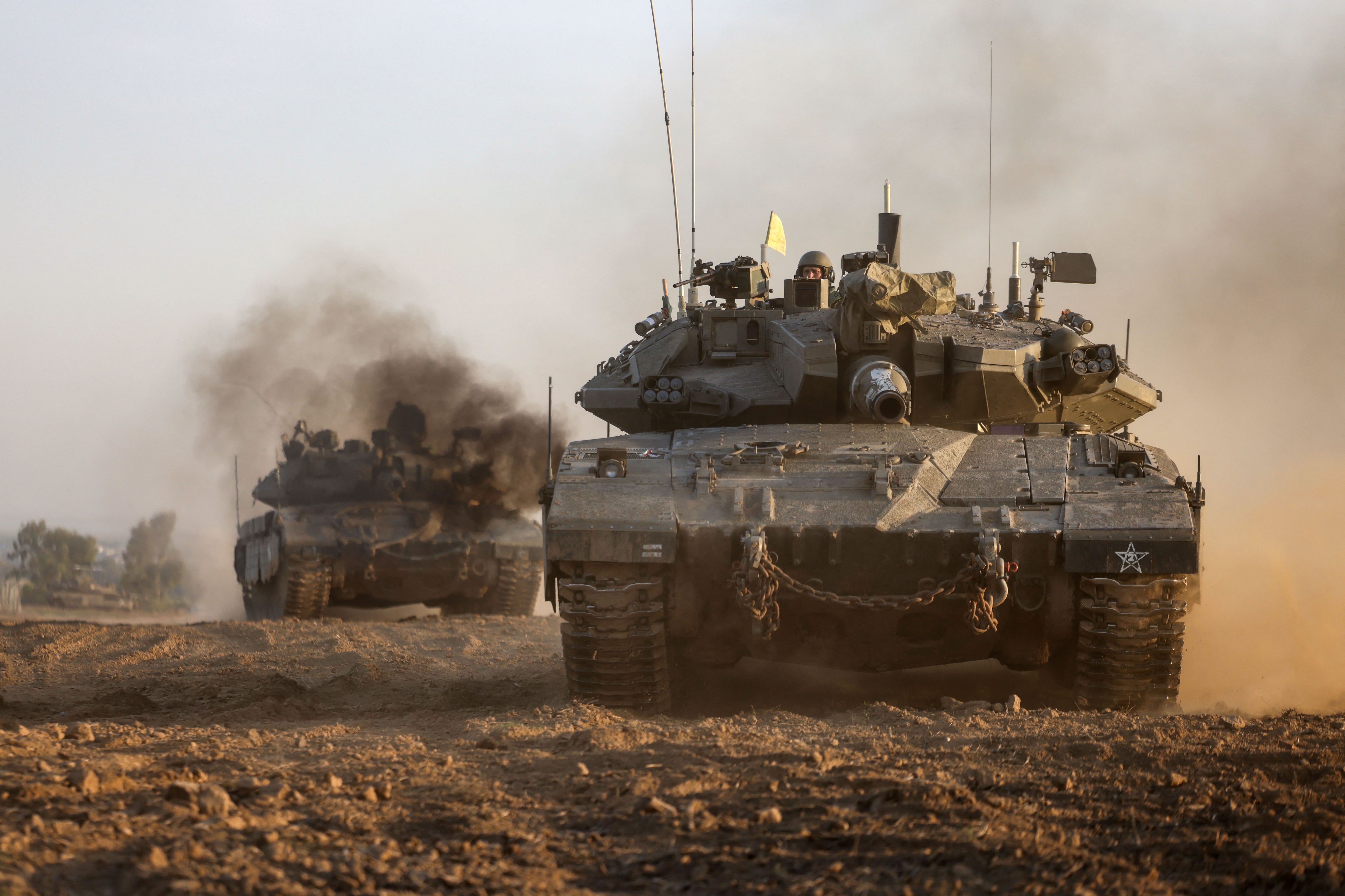 Israeli military tanks pass near the border with the Gaza Strip on December 3, 2023, amid ongoing battles with the militant group Hamas.  (Photo by Menahem KAHANA/AFP).