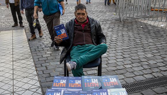 Un vendedor posa con un libro de la nueva Constitución que se vende al público en las calles de Santiago, el 12 de julio de 2022. La campaña por el plebiscito del 4 de septiembre para aprobar o rechazar el texto de una nueva Constitución comenzó el 6 de julio en Chile. Foto: MARTÍN BERNETTI / AFP