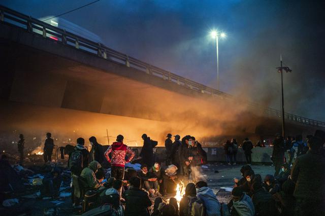 Los migrantes prendieron fuego a diversos objetos para calentarse mientras esperaban ser evacuados por las fuerzas policiales en Saint-Denis, al norte de París, Francia. (EFE/EPA/YOAN VALAT).
