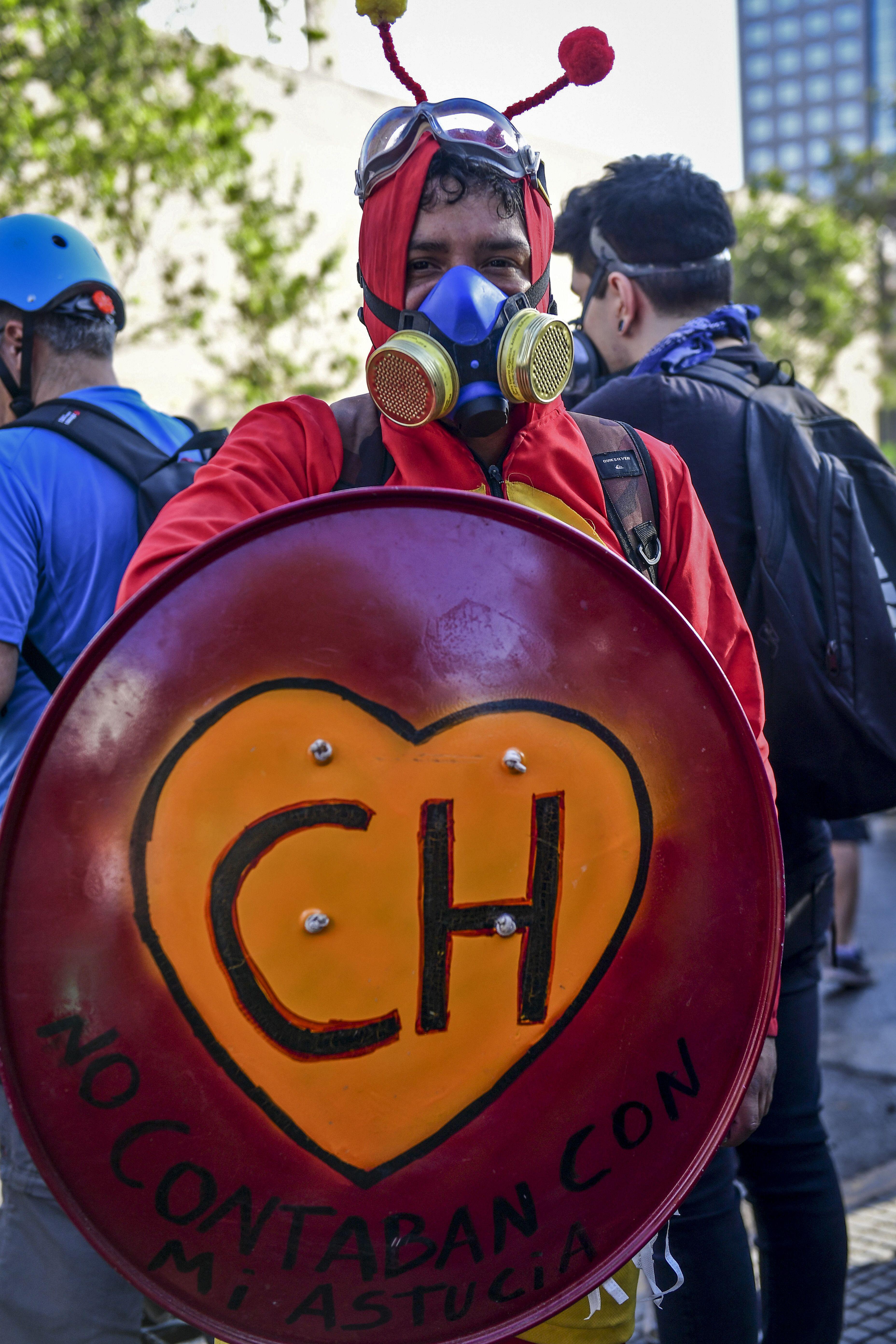 Un manifestante disfrazado de El Chapulín Colorado sostiene un escudo durante una protesta contra el gobierno en Santiago. (Foto por Martin BERNETTI / AFP).