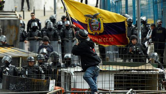 Un manifestante ondea una bandera de Ecuador mientras policías montan guardia en los alrededores de la Asamblea Nacional en Quito el 25 de junio de 2022. (RODRIGO BUENDIA / AFP).