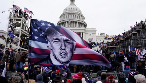 Foto del 6 de enero de 2021 donde aparecen varios simpatizantes de Donald Trump ondeando banderas con su imagen durante el asalto al Capitolio. (EFE/EPA/Will Oliver).