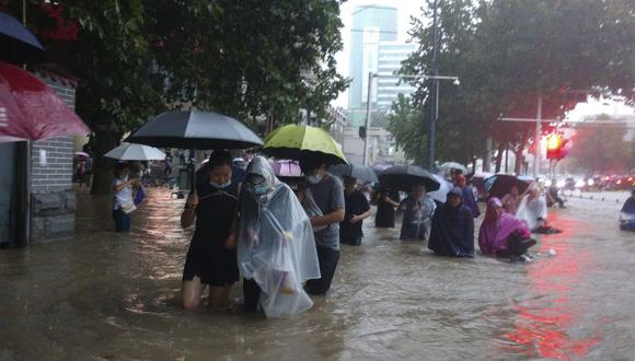 Las personas se mueven a través del agua de la inundación después de un fuerte aguacero en la ciudad de Zhengzhou, provincia de Henan, en el centro de China, el martes 20 de julio de 2021. (Chinatopix/AP).