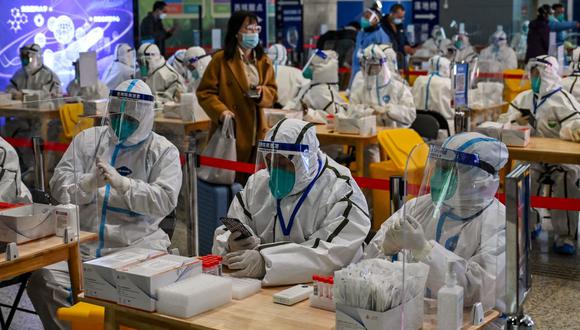 Trabajadores de la salud esperan para evaluar a pasajeros por el coronavirus Covid-19 en la estación de tren de Hongqiao, en Shanghái, el 6 de diciembre de 2022. (HECTOR RETAMAL / AFP).