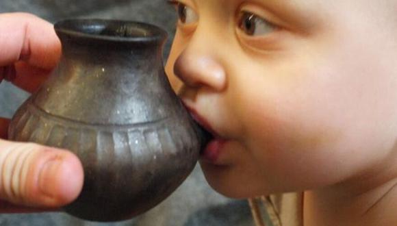 Un bebés es alimentado con el modelo de un biberón prehistórico. (Foto: Helena Seidl da Fonseca)