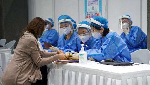 Los trabajadores médicos recopilan información de un periodista extranjero (izquierda) que espera ser inoculado con la vacuna Covid-19, en una clínica improvisada para vacunar a periodistas extranjeros que trabajan en la capital, en el Museo de Planificación Urbana Chaoyang en Beijing. (Foto: Archivo/ Noel Celis / AFP)