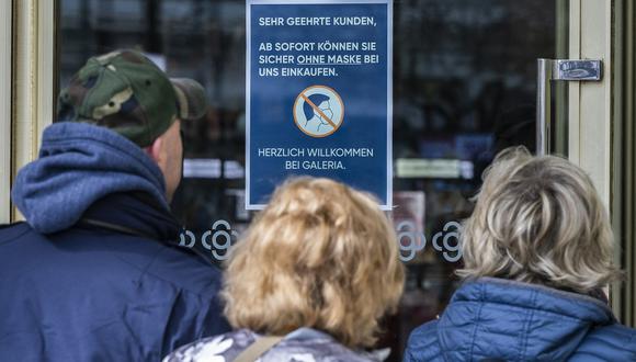 Un letrero en la puerta de una tienda por departamentos de Berlín dice: "A partir de ahora, puede comprar de manera segura sin usar mascarilla", mientras los compradores entran el 1 de abril de 2022. (Foto de John MACDOUGALL / AFP)