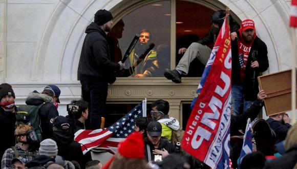 Una multitud de simpatizantes del entonces presidente de Estados Unidos, Donald Trump trepa por una ventana que rompieron mientras asaltan el edificio del Capitolio el 6 de enero del 2021.