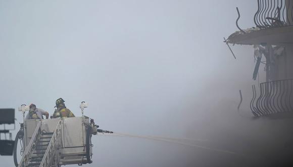 Los bomberos vierten agua sobre el condominio Champlain Towers South mientras el humo espeso de un incendio llena el aire en Surfside, Florida, el viernes 25 de junio de 2021. (AP/Wilfredo Lee).