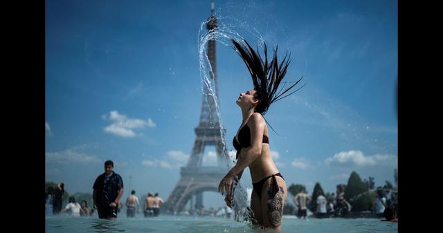 Una mujer se refresca en la fuente de la Explanada de Trocadero, en París (Francia), con la Torre Eiffel al fondo. (Kenzo TRIBOUILLARD / AFP).