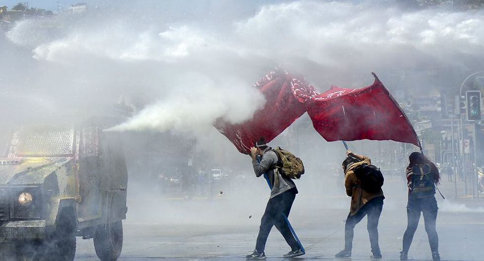 A police vehicle spray tear gas at anti-government protesters in Valparaiso, Chile, Friday, Oct. 25, 2019. A new round of clashes broke out Friday as demonstrators returned to the streets, dissatisfied with economic concessions announced by the government in a bid to curb a week of deadly violence.(AP Photo/Matias Delacroix)