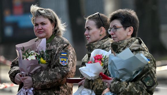 Las mujeres militares ucranianas llevan flores mientras caminan en el centro de Kiev después de una ceremonia de premiación para las mujeres militares ucranianas en el Día Internacional de la Mujer el 8 de marzo de 2023. (Foto de Sergei SUPINSKY / AFP)