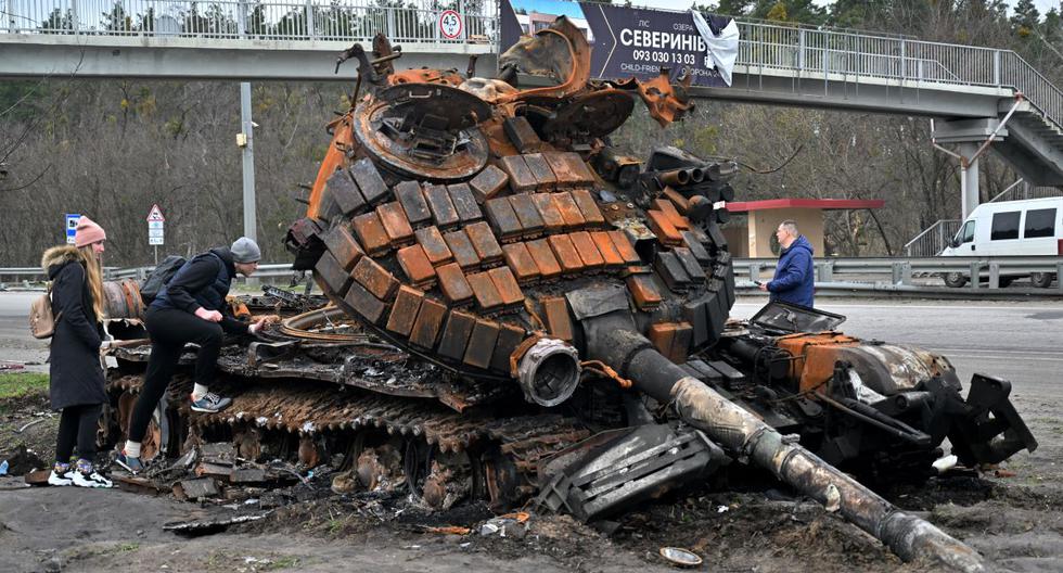 Los residentes observan un tanque ruso destruido en las afueras de la aldea de Buzova, al oeste de Kiev, Ucrania, el 10 de abril de 2020. (Sergei SUPINSKY / AFP).