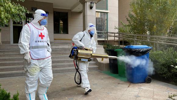 Trabajadores desinfectan un complejo residencial en Lanzhou, en la provincia de Gansu, noroeste de China, el 26 de octubre de 2021, en medio de la pandemia de coronavirus. (STR / AFP).