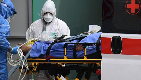 Trabajadores médicos atienden a un paciente de coronavirus en una ambulancia de la Cruz Roja en Milán, Italia. (Foto: AFP)