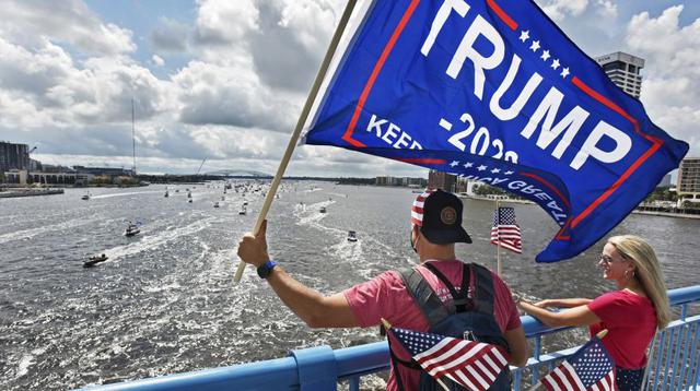 Unos manifestantes ondean banderas en los cientos de barcos que ralentizan en el río St. Johns durante un mitin en Jacksonville, Florida, celebrando el cumpleaños del presidente Donald Trump. (Foto: Will Dickey / AP).