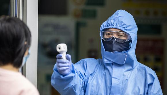 Un guardia de seguridad que usa equipo de protección mide la temperatura corporal de los visitantes en la entrada de un banco en Guangzhou, provincia de Guangdong, China. (EFE / EPA / ALEX PLAVEVSKI).