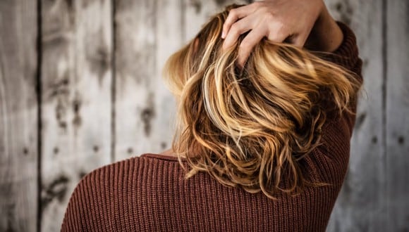 Una mujer de espaldas agarrándose su cuero cabelludo. | Imagen referencial: Unsplash