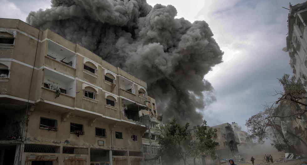 Los palestinos se apresuran a buscar refugio mientras se eleva el humo después del bombardeo de Israel en el centro de la ciudad de Gaza el 18 de marzo de 2024. (Foto de AFP).