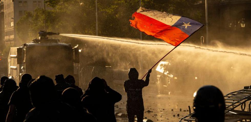 Los manifestantes son rociados por un cañón de agua de la policía antidisturbios durante los enfrentamientos luego de una protesta contra el gobierno del presidente chileno Sebastián Piñera en Santiago. (AFP / Martin BERNETTI).
