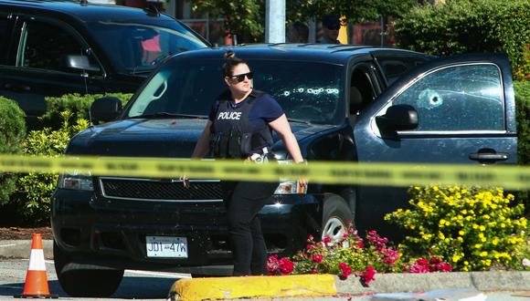 Un oficial de policía camina junto a un automóvil con agujeros de bala en las ventanas en la escena del crimen en el suburbio de Langley, Columbia Británica, Canadá.