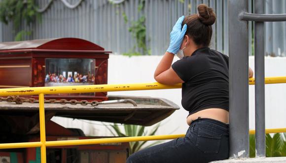 Una mujer con una máscara facial y guantes llora mientras espera el cadáver de un pariente frente a un hospital en Guayaquil, Ecuador. (Foto: AFP / Enrique Ortiz).