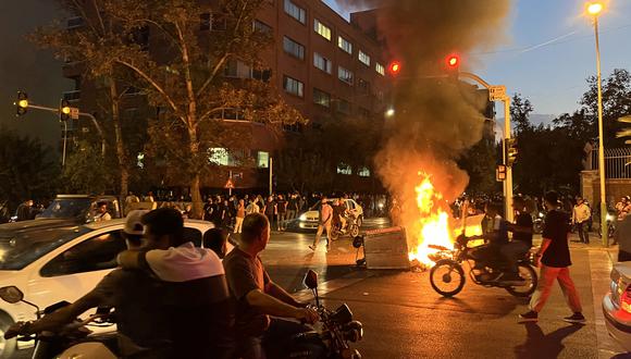 Manifestantes reunidos alrededor de una barricada en llamas durante una protesta por Mahsa Amini, una mujer que murió después de ser arrestada por la "policía de la moralidad" de la república islámica, en Teherán el 19 de septiembre de 2022. (Foto: AFP)