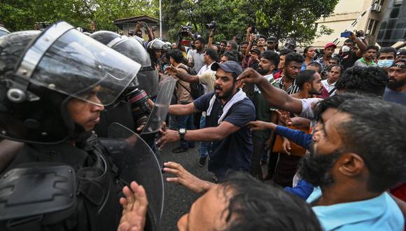 Policías hacen guardia mientras los manifestantes participan en una manifestación de protesta contra el gobierno que exige la liberación de los líderes de los estudiantes universitarios y contra el aumento del costo de vida, en Colombo el 2 de noviembre de 2022. (Foto de Ishara S. KODIKARA / AFP)
