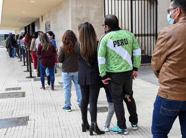 Peruanos residentes en España hacen cola para ejercer su derecho al voto en las elecciones generales de su país este domingo en el Auditorium de Palma de Mallorca. (EFE/CATI CLADERA).
