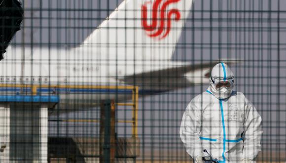 Un trabajador con un traje protector camina cerca de un avión de las aerolíneas Air China en el Aeropuerto Internacional de Beijing Capital mientras continúan los brotes de la enfermedad por coronavirus (COVID-19) en Beijing, China.