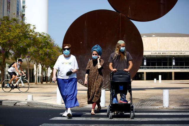 Personas con mascarillas cruzan una avenida antes de un cierre nacional para contener la propagación del coronavirus (COVID-19), que comenzará el viernes, en Tel Aviv, Israel. (REUTERS/Corinna Kern).
