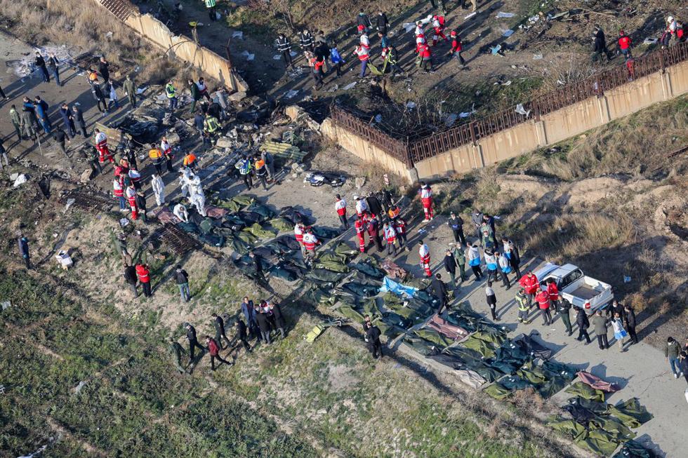 Miembros del equipo de rescate y voluntarios son captados en medio de los  cuerpos y escombros después de que un avión ucraniano que transportaba a 176 pasajeros se estrellara cerca del aeropuerto Imán Jomeiní, en la capital iraní, Teherán. (AFP)