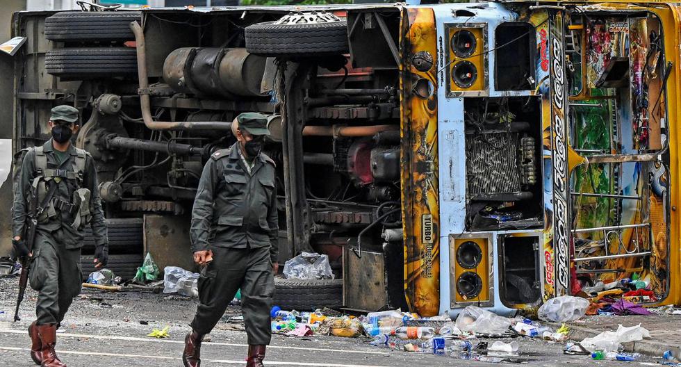 El personal de seguridad pasa junto a un vehículo quemado en Colombo, capital de Sri Lanka, el 10 de mayo de 2022. (ISHARA S.KODIKARA / AFP).