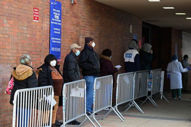 Las personas usan mascarillas para protegerse del coronavirus. Ellos hacen fila afuera de un sitio de prueba COVID-19 en Gotham Health (Foto: Angela Weiss / AFP)