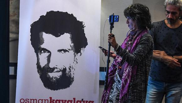 Un periodista se para frente a un cartel con el empresario y filántropo encarcelado Osman Kavala durante una conferencia de prensa de sus abogados en octubre de 2018. En ese entonces, Kavala cumplía un año arrestado por las autoridades turcas. (OZAN KOSE / AFP)