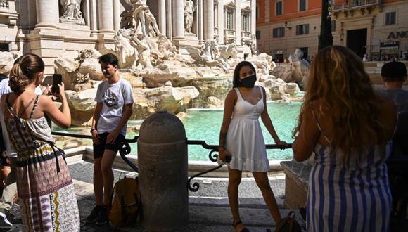 Un turista con máscara facial (centro) posa para una foto con la fuente de Trevi en el centro de Roma durante la infección por COVID-19, causada por el nuevo coronavirus. (Foto: AFP / Vincenzo PINTO).