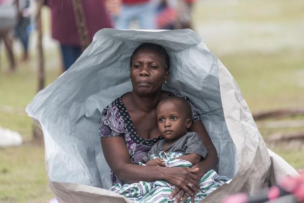A Haiti earthquake victim and her son protect themselves as best they can from Tropical Storm Grace near Les Cayes. (REGINALD LOUISSAINT JR / AFP).
