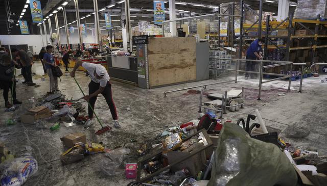 Trabajadores de un supermercado limpian los escombros que dejaron los saqueadores. (AP Photo/Esteban Felix).