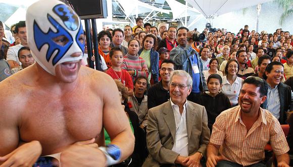 El escritor peruano Mario Vargas Llosa (C) observa una pelea de Lucha Libre el 27 de noviembre de 2005, en la explanada del recinto que alberga la XIX Feria Internacional del Libro. En 2021, el Perú vuelve a ser país invitado. (Foto: Iván García para AFP)