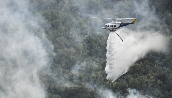 Un helicóptero rocía agua sobre un incendio forestal cerca del pueblo de Lafki, en la isla griega de Corfú. (Foto de Armend NIMANI / AFP)