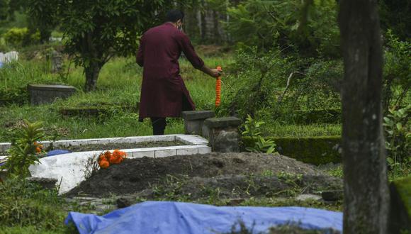 Imagen referencial de una persona colocando flores en una tumba, el 21 de julio de 2021. (PRAKASH MATHEMA / AFP).