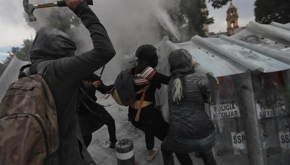 Mujeres activistas usan martillos para enfrentarse con la policía en las afueras del Palacio Nacional de México. (EFE/Sáshenka Gutiérrez).