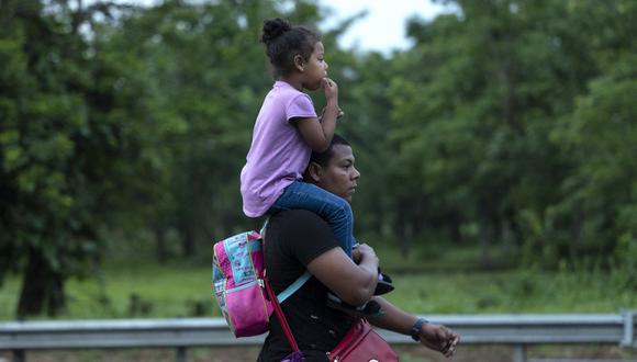 Un migrante que forma parte de una caravana que se dirige a los EE. UU. carga a una niña sobre sus hombros mientras camina de Huixtla a Escuintla, estado de Chiapas, México.