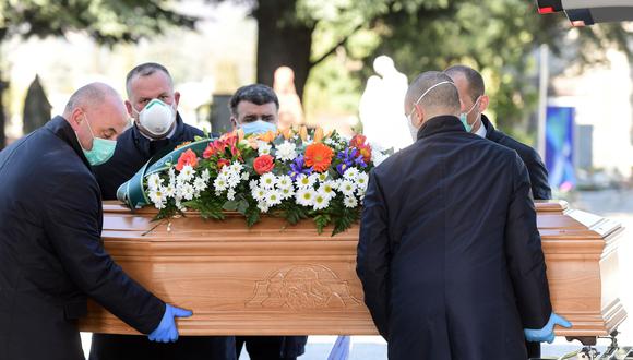 Italia, primer país europeo que confinó a su población, fue todavía más lejos al suspender todas las ceremonias religiosas, “incluidos los entierros”. Imagen de personas descargando un ataúd en el cementerio de Bérgamo. (AFP/Referencial).