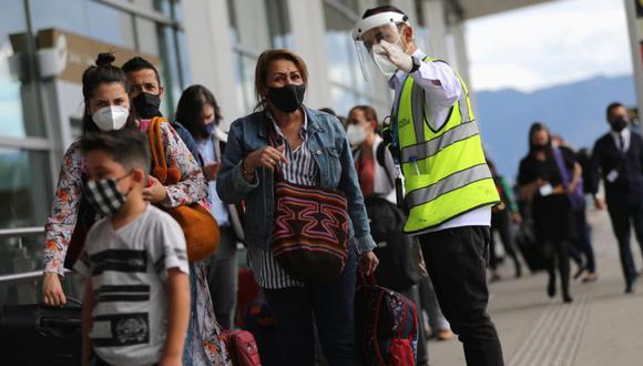 Un empleado del Aeropuerto Internacional El Dorado con una pantalla facial y una máscara da instrucciones a una pasajera en Bogotá, Colombia. (Foto: REUTERS / Luisa Gonzalez).