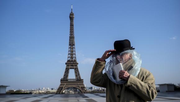 Un hombre usa una bolsa de plástico para protegerse del coronavirus cerca de la Torre Eiffel en París (Francia). (EFE/EPA/Julien de Rosa).