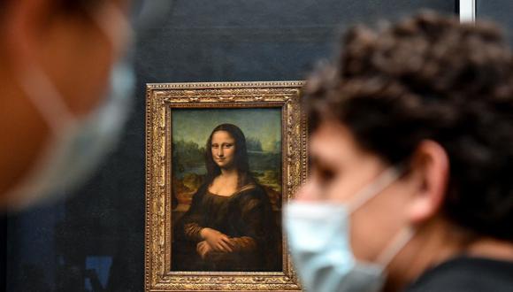 Los visitantes pasan junto a la pintura La Mona Lisa del artista italiano Leonardo Da Vinci que se exhibe en la "Salle des Etats" del Museo del Louvre en París el 19 de mayo de 2021. (Foto de ALAIN JOCARD / AFP).