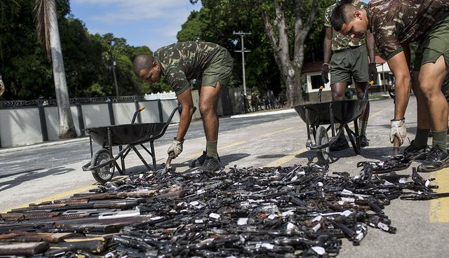 Military personnel pick up trashed weapons that were confiscated by the Federal Police in Rio de Janeiro, Brazil, Friday, June 2, 2017. Around 4000 weapons some seized during operations and others that people voluntarily delivered to the police in the last 2 years were crushed with a Brazilian Army steam roller. (AP Photo/Silvia Izquierdo)