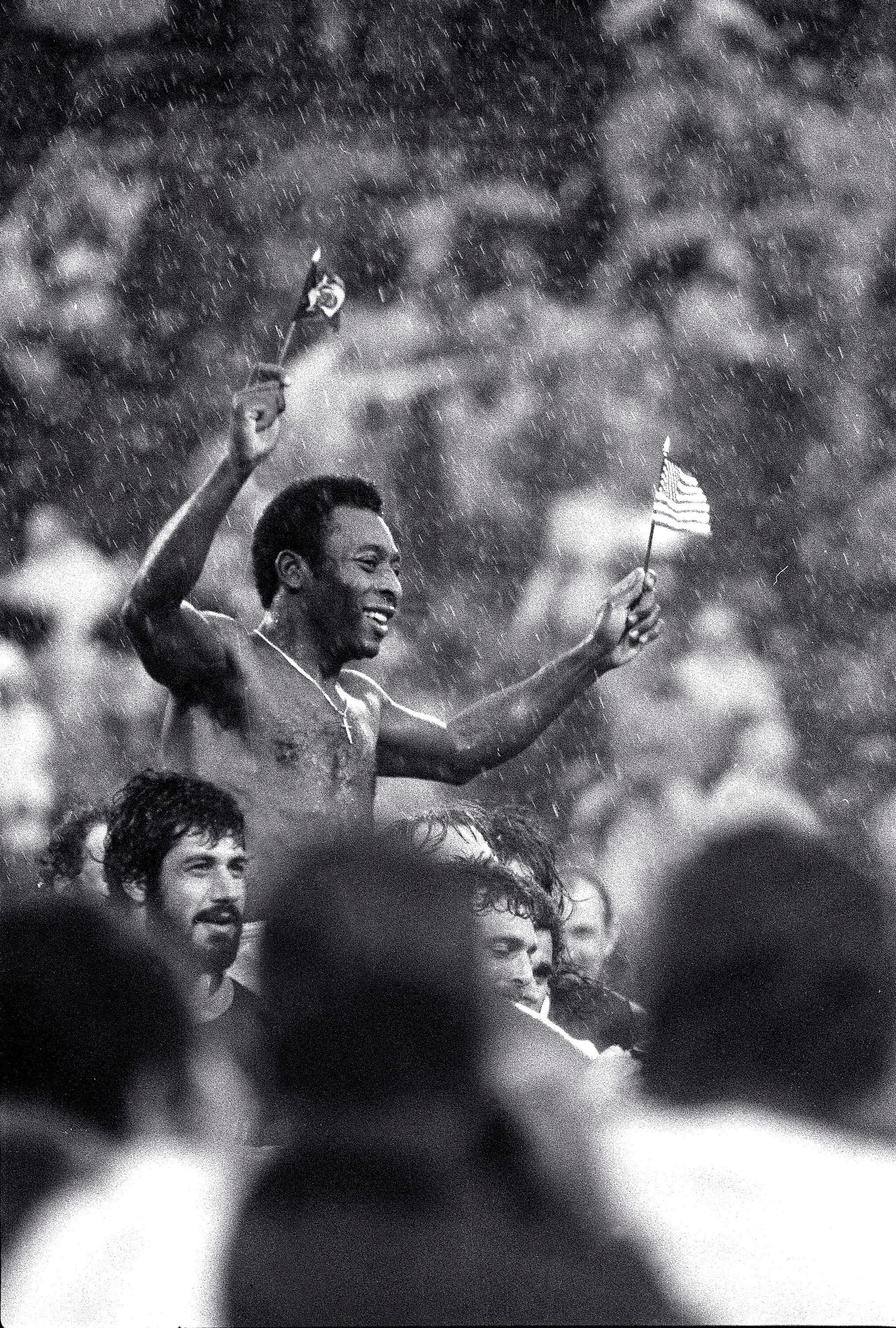 FILE - Soccer superstar Pele, waving the flags of Brazil and the U.S., is carried off the field in driving rain by players of both teams at Giants Stadium in East Rutherford, N.J., after his final game, Oct. 1, 1977. Pelé, the Brazilian king of soccer who won a record three World Cups and became one of the most commanding sports figures of the last century, died in Sao Paulo on Thursday, Dec. 29, 2022. He was 82. (AP Photo/Richard Drew, File)